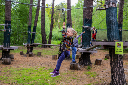 A young cheerful smiling girl standing in a safety ropes at adventure parkの写真素材