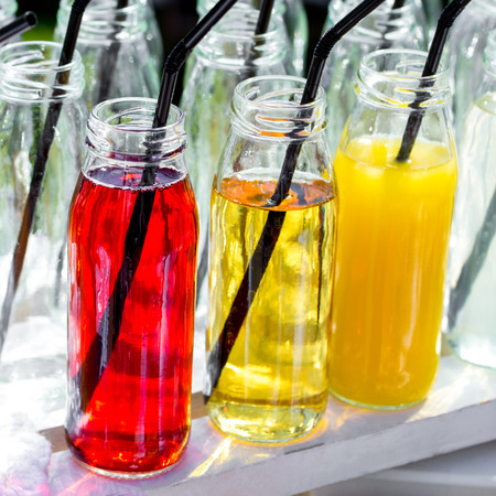 Colorful cocktails or juices, shots with straws in small glass bottles.の写真素材