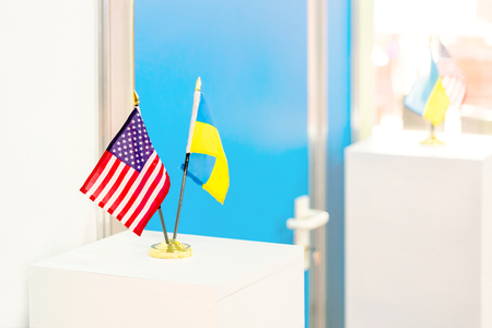 Ukrainian and USA flags stand together. Closed door on the background. Government negotiations. Partnership and cooperation concept.  の写真素材
