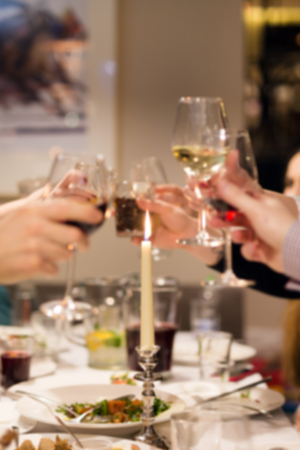 Blurred abstract background of clinking glasses of wine. Cheers after speech. Party at cafe or restaurant. Family celebration or anniversaryの写真素材