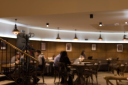 Blurred abstract restaurant background. Warm evening colors of cafe interior. Vintage defocused bar hall.の写真素材