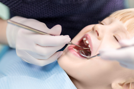 Baby girl  visiting stomatology clinic. Dentist making checkup of kids teeth. Children tooth and mouth healthcare.の写真素材