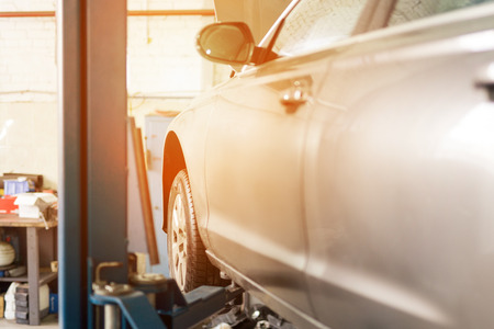 Car at service center. Vehicle raised on a lift. Check up, maintenance and repair conceptの写真素材