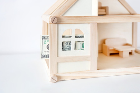 Wooden house model with 100 dollar bill. House rental and sale. Expenses and costs for house handling. Housing savings concept.  Copyspace.の写真素材