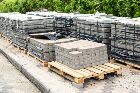 Row of stacks of gray pavement slab on wooden base. Concrete stone paving flag. Isolated on whiteの写真素材