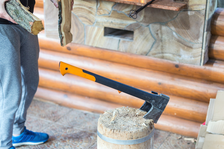 Man holding firewoods for brazier in summerhouse. Wood chopping with modern axe for barbecue partyの写真素材