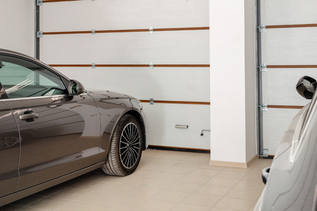 Home garage for two vehicles interior. Clean luxury cars parked at home. Automatic remote control doors. Transport roofed storage.の写真素材