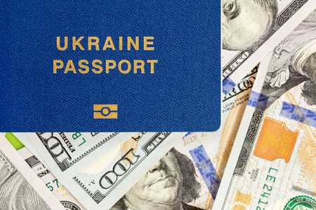 Biometrical Ukrainian passport over money background. Ukraine citizen travel documents lying on US one hundred dollar banknotes.の写真素材