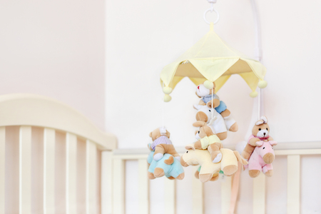 Close-up baby crib with musical animal mobile at nursery room. Hanged developing toy with plush fluffy animals. Happy parenting and childhood, expectation delivery of a child conceptの写真素材