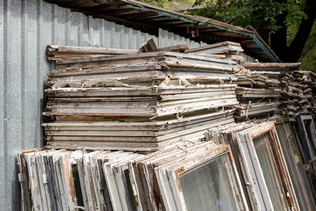 Heap of old wooden window frames with glass outdoors. Broken materials after window energy saving technology upgrade.の写真素材