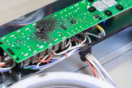 Burnt green microchip after short circuit due to water damage. Damaged overheat control panel board...