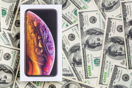 Latest Iphone XS in unopened box on US dollar banknotes background.のeditorial素材