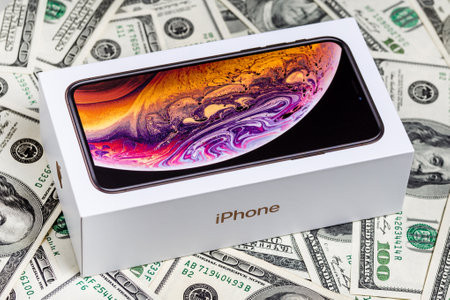 Latest Iphone XS in unopened box on US dollar banknotes background.のeditorial素材