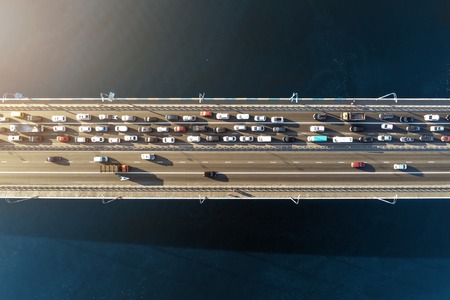 Aerial view of road bridge across river with heavy traffic jam in one direction. Rush hour with mash and overloading of road infrastructure. Resolving of car traffic jam.の写真素材