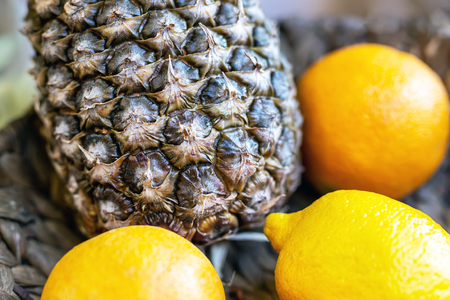 Close-up pineapple and citrus tropical fruits on dark dish bowl. Hotel room welcome gift.の写真素材