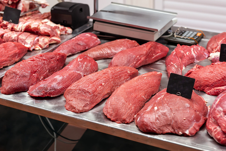 Assortment of raw beef fillet meat at farmers market. Metal counter with many big slabs of fresh veal and pork at wholesale butcher store.の写真素材