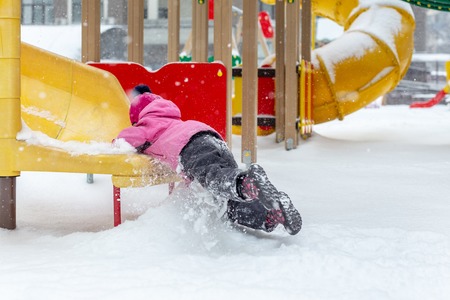 Little cute baby girl having fun on playground at winter. Children winter sport and leisure outdoor activities.の写真素材