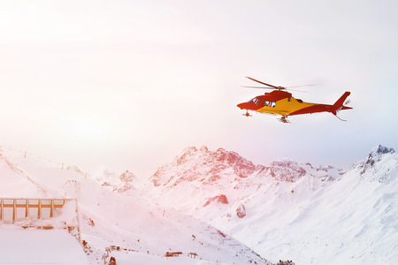 Rescue helicopter landing on slopes at ski resort in alpine mountains. Emergency accident service.の写真素材