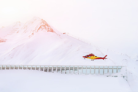 Rescue helicopter landing on slopes at ski resort in alpine mountains. Emergency accident service.の写真素材