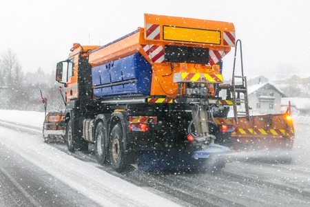 Snowplow truck removing dirty snow from city street or highway during heavy snowfalls. Traffic road situation. Weather forecast for drivers. Seasonal road maintenanceの素材 [FY310116759963]