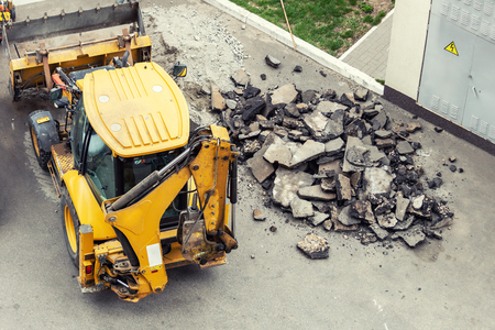 Big jackhammer drill drilling road.Heavy machinery crushing asphalt for stormwater drain repairの写真素材