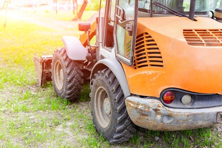 Wheel loader machine on grass field in park area. Municipal works on reconstruction and renewal city recreation area. Heavy and light machinery rental.の写真素材