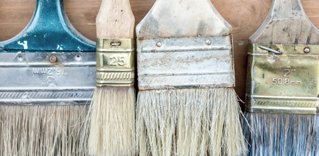 Close-up set of old used pant brushes on rustic wooden background. Vintage dirty paintbrushesの写真素材