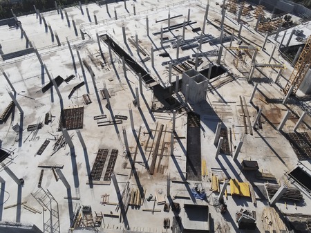 Construction site aerial view. Mall building base with solid concrete pillars. Heavy machinery and...