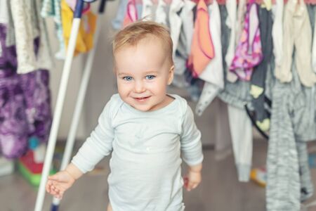 Cute adorable caucasian toodler boy laughing and hving fun playing home with mess and clothes dryer on background. portrait of Funny playful baby at nursery room. Happy and carefree childhood concept.の写真素材