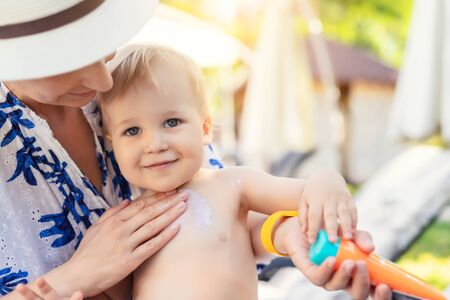 Mother applying sunscreen protection creme on cute little toddler boy face. Mom using sunblocking lotion to protect baby from sun during summer sea vacation. Children healthcare at travel time.の写真素材