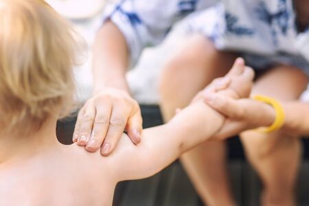 Mother applying sunscreen protection creme on cute little toddler boy shoulder. Mom using...