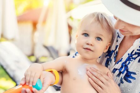Mother applying sunscreen protection creme on cute little toddler boy face. Mom using sunblocking lotion to protect baby from sun during summer sea vacation. Children healthcare at travel time.の写真素材