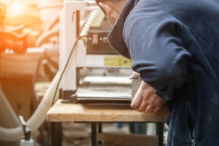 Craftsman woodworking at carpentry with lots of modern professional power tools. Man using thickness planer machine and circular saw and other equipment at workshop.の写真素材