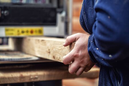 Craftsman woodworking at carpentry with lots of modern professional power tools. Man using thickness planer machine and circular saw and other equipment at workshop.の写真素材