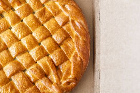 Traditional homemade rustic baked pie with seasonal fruit or meat filling in cardboard box. Fast food to go. Bakery delivery menu. Flat lay. Copyspace.の写真素材