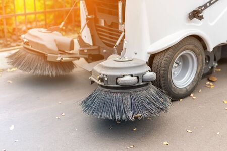 Small sweeper machine standing at parking storage after cleaning city park alley.Sweeping vacuum cleaner vehicle removing dust and fallen leaves in autumn.の写真素材
