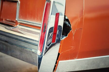 Close-up old retro car wrecked tail wing part with big rusty hole after accident. Vintage vehicle restoration and repair.の写真素材