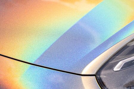 Close-up LED headlight expensive car part with exclusive iridescent painting. Vehicle covered with vibrant chameleon film.の写真素材