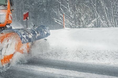 Snowplow truck removing dirty snow from city street or highway after heavy snowfalls. Traffic road situation. Weather forecast for drivers. Seasonal road maintenance.の写真素材