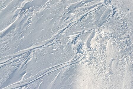 Snowy abstract off-piste skiing backround texture with ski and snowboard trails and tracks on new...
