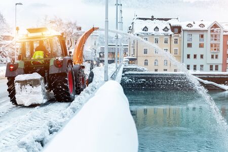 Heavy municipal services machinery removing snow from city streets. Big tractor snowblower blowing...
