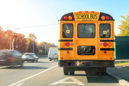 Big classic vintage american yellow schoolbus standing on a bus lane at highway and waiting pupils...