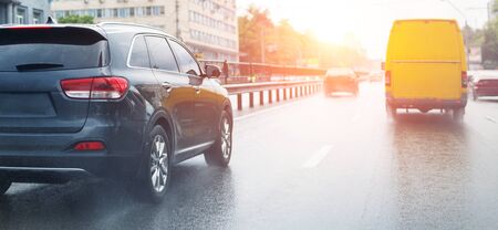 Cars moving fast by wet highway after heavy rain with warm sunset evening sun on background....