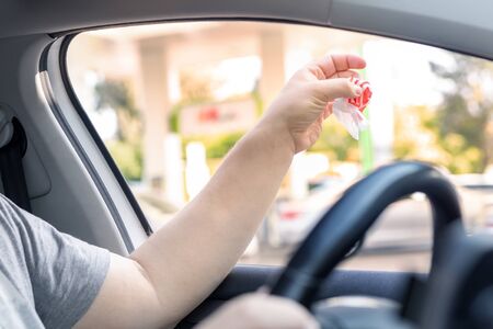 Adult male person throwing out paper fast food snack wrap garbage in window driving car on sunny day. Man hand tossing waste outside vehicle. Irresponsible bad manner behaviour norms. nature pollutionの写真素材
