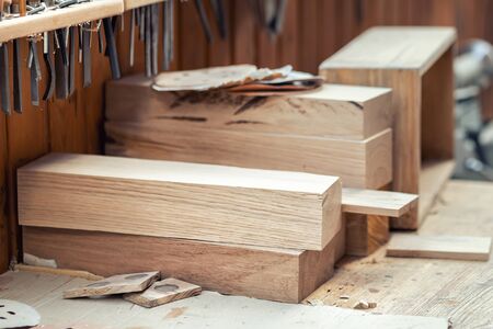 Oak wooden bar blocks materials stacked at carpentry woodwork workshop with tools and sawdust on background. Timber wood blanks at diy workbench. Close-up lumber beam details. Handcraft hobby.の写真素材