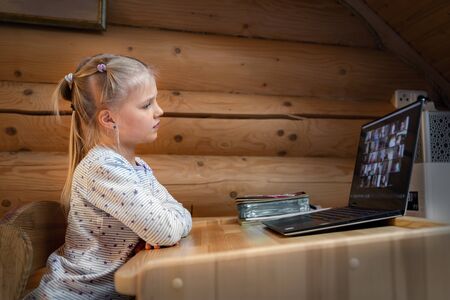 Cute adorable caucasian little blond girl sitting at desk with laptop during online video chat...