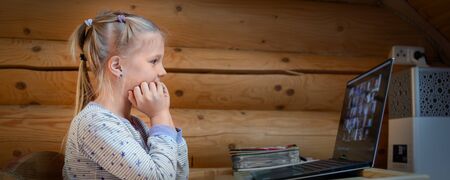 Cute adorable caucasian little blond girl sitting at desk with laptop during online video chat...