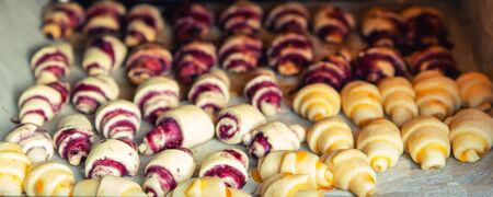 Grandmother making handmade tasty butter rolling cookies with fruit and berry jam on oven tray before baking at kitchen indoor. Rolled spin homemade healthy pastry preparing.の写真素材