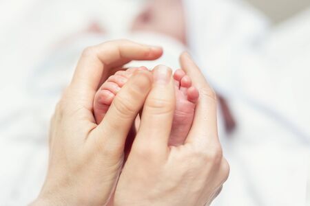 Mother making baby feet massage for newborn infant child. Mom massaging legs of small baby son.Children healthcare and happy parenthood.の写真素材