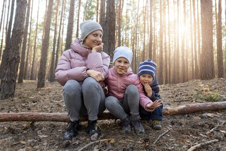 Young small cute adorable cheerful playful caucasian toddler boy enjoy having fun walking at spring or autumn forest and eating snack stick biscuits outdoor. Healthy outside nature family activityの写真素材